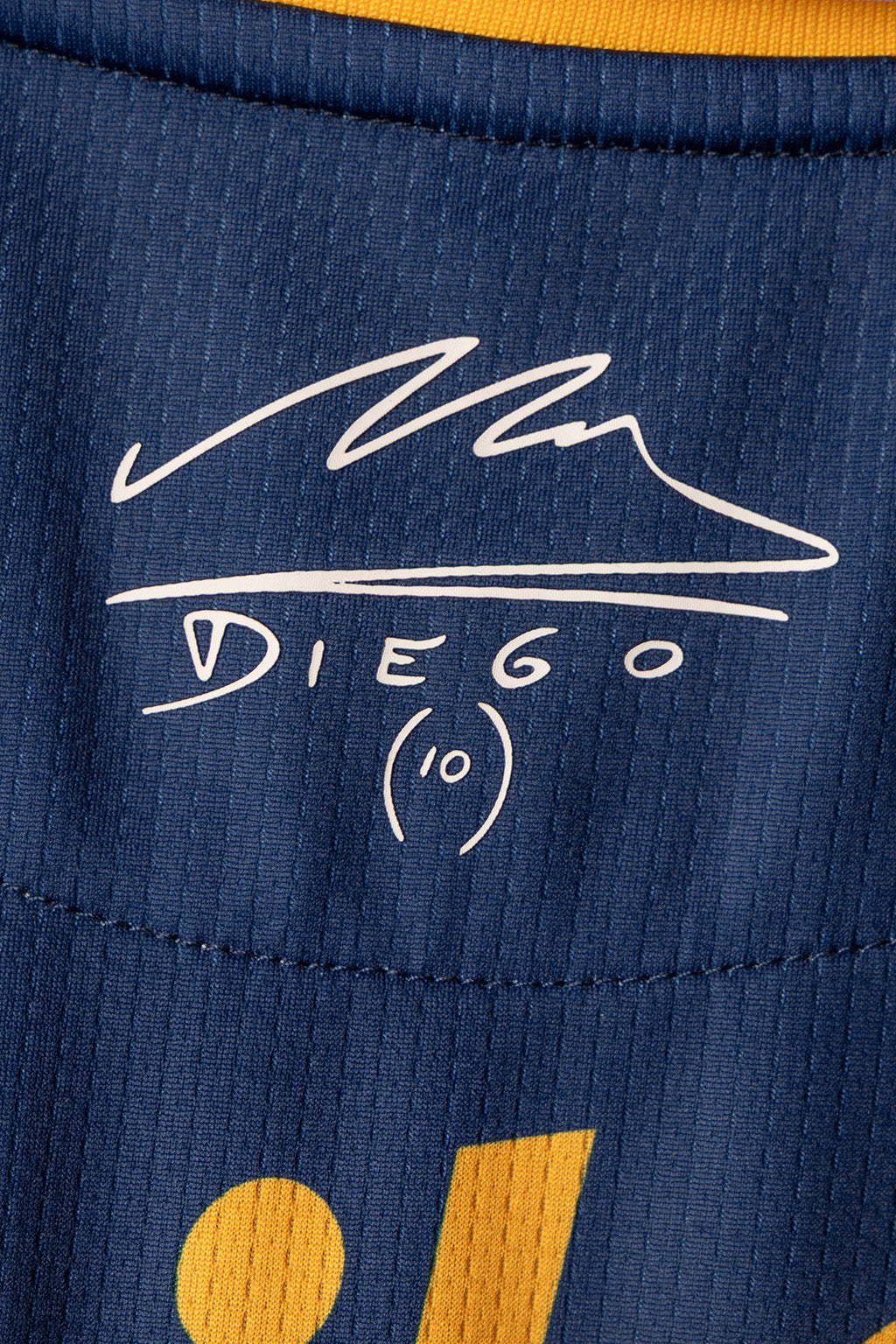 Close-up of a navy blue athletic jersey with a white embroidered signature reading 'Diego' and the number 10, plus yellow accents at the collar and bottom.