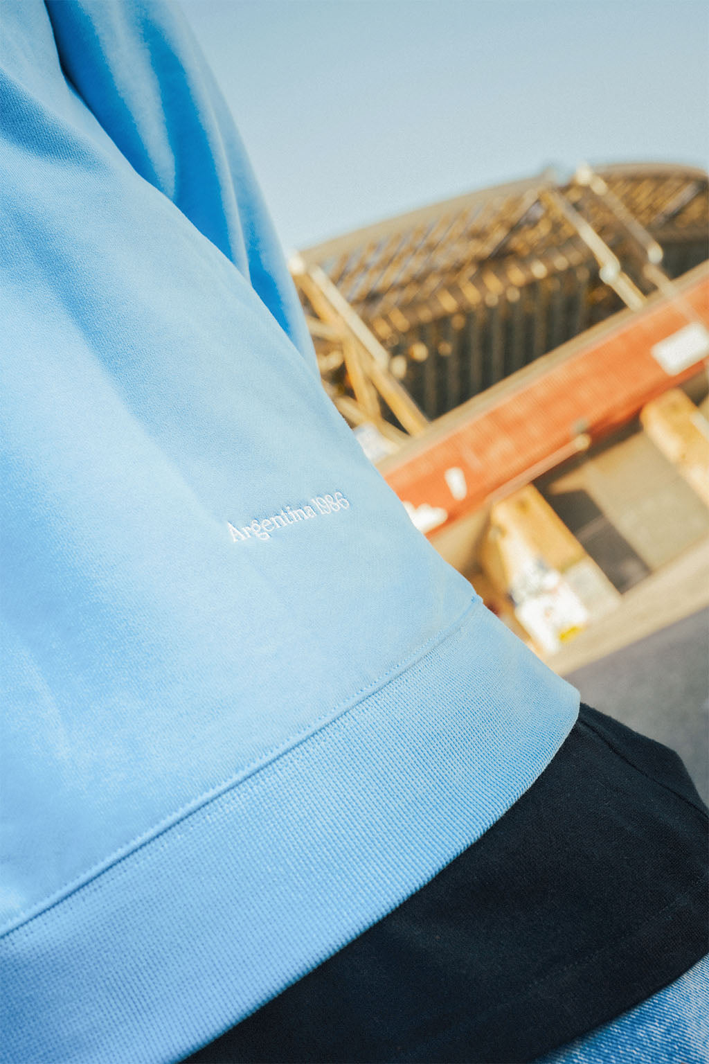 Close-up of a blue garment with Maradona Argentina 1986 branding, blurred stadium background