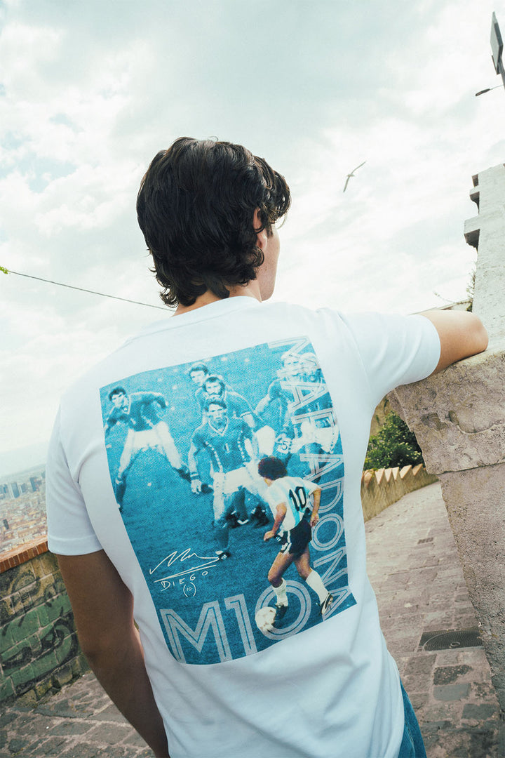 Man wearing a white t-shirt with a graphic Maradona 86 design outdoors 