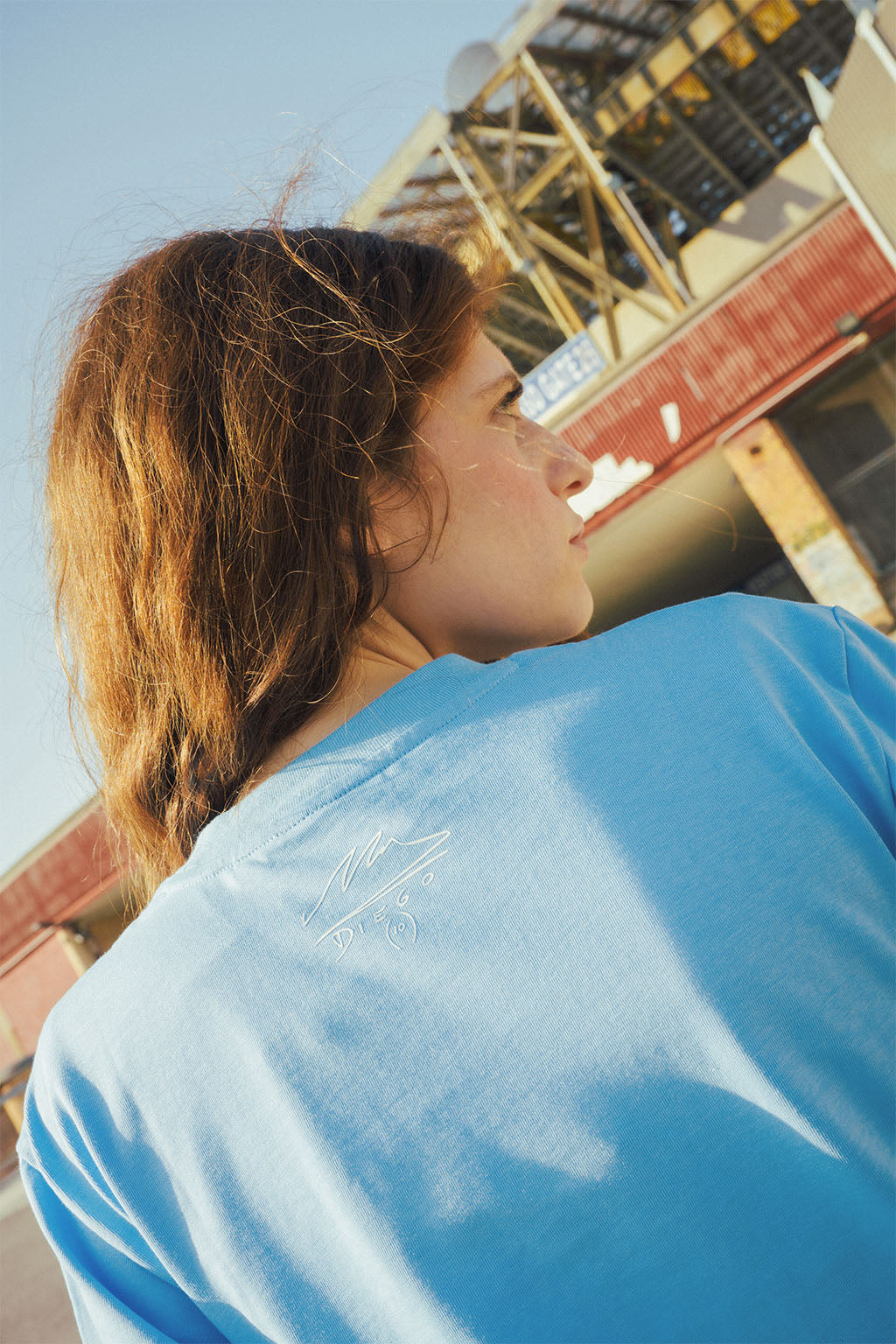 Woman wearing a blue Maradona signature shirt with a blurred stadium background