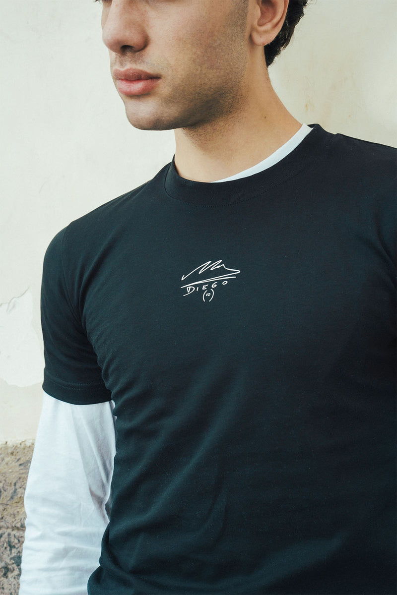 Man wearing a black t-shirt with a Maradona signature logo on a light stone background