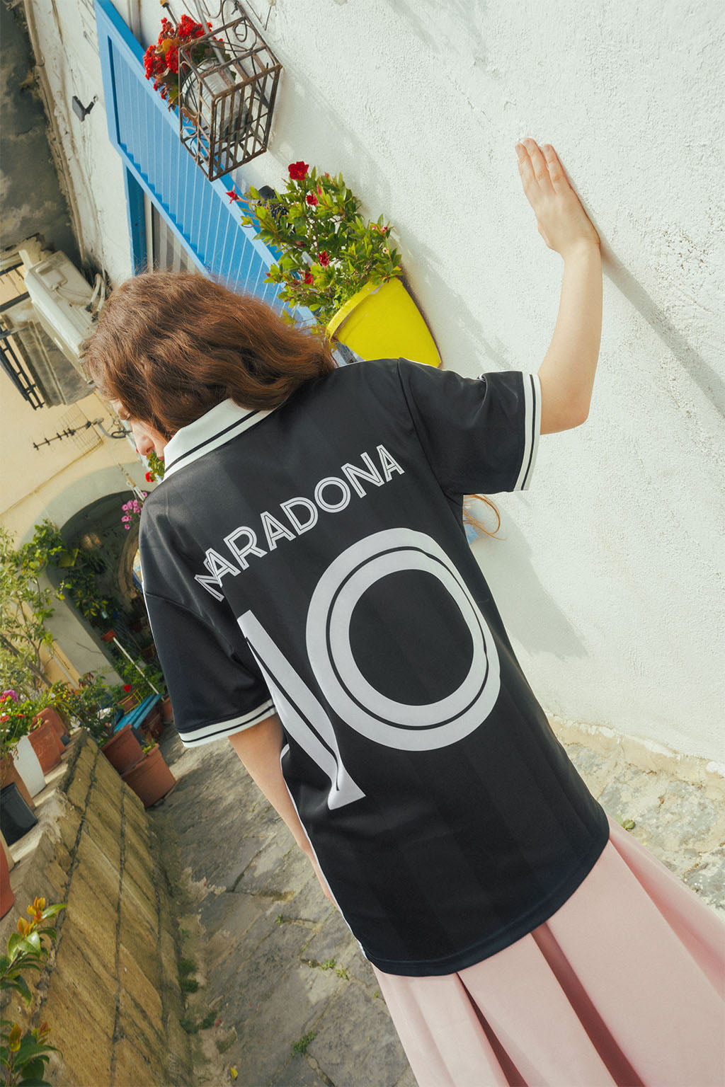 Woman wearing a signature black Maradona jersey with '10' printed on it, standing in an outdoor urban setting.