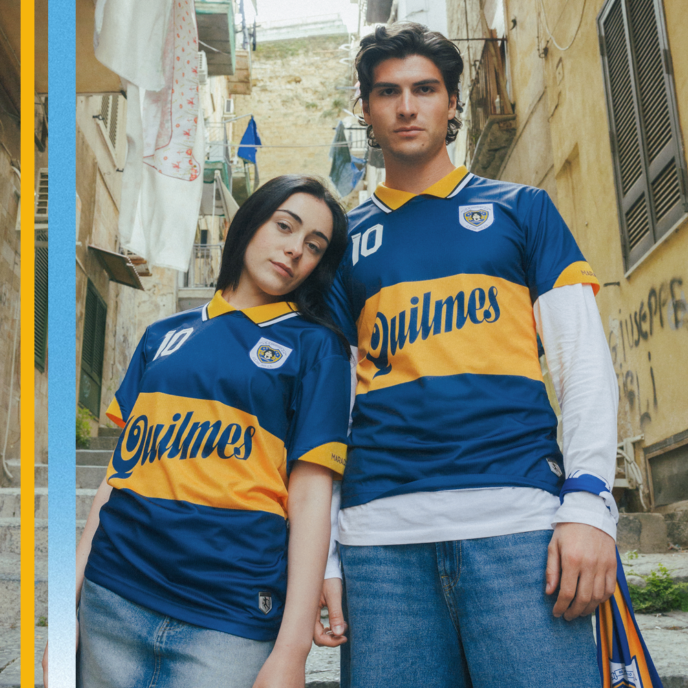 Two people wearing Boca Juniors Maradona jerseys standing in an alleyway.